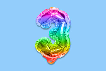 Rainbow foil balloon number, digit three on a blue background. Birthday greeting card with inscription 3. Top view. Numerical digit. Celebration event template.の写真素材