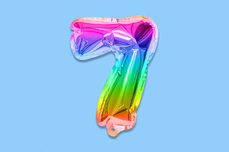 Rainbow foil balloon number, digit seven on a blue background. Birthday greeting card with inscription 7. Top view. Numerical digit. Celebration event, template.の写真素材