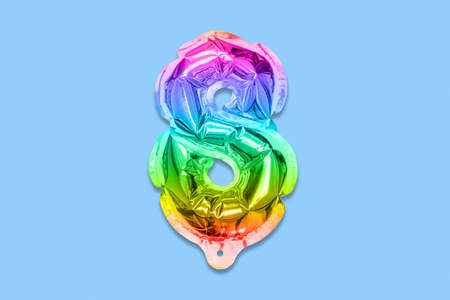 Rainbow foil balloon number, digit eight on a blue background. Birthday greeting card with inscription 8. Top view. Numerical digit. Celebration event, template.の写真素材