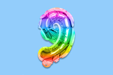 Rainbow foil balloon number, digit nine on a blue background. Birthday greeting card with inscription 9. Top view. Numerical digit. Celebration event, template.の写真素材