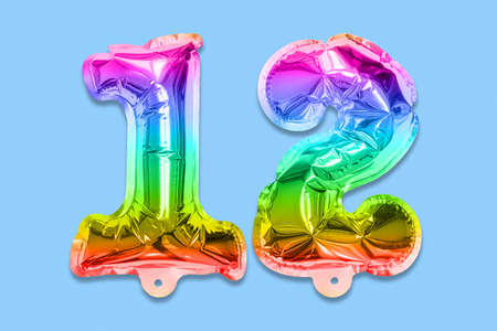 Rainbow foil balloon number, digit twelve on a blue background. Birthday greeting card with inscription 12. Top view. Numerical digit. Celebration event template.の写真素材