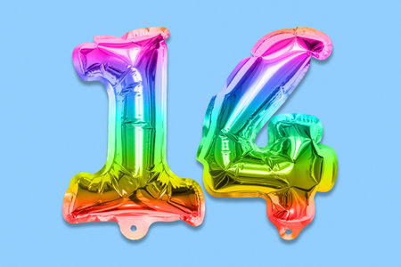 Rainbow foil balloon number, digit fourteen on a blue background. Birthday greeting card with inscription 14. Anniversary concept. top view. Numerical digit. Celebration event template.の写真素材