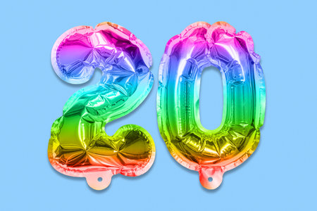 Rainbow foil balloon number, digit twenty on a blue background. Birthday greeting card with inscription 20. Anniversary concept. top view. Numerical digit. Celebration event template.の写真素材