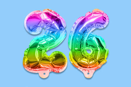 Rainbow foil balloon number, digit twenty six on a blue background. Birthday greeting card with inscription 26. Top view. Numerical digit. Celebration event template.の写真素材