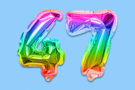 Rainbow foil balloon number, digit forty seven on a blue background. Birthday greeting card with inscription 47. Top view. Numerical digit. Celebration event template.の写真素材