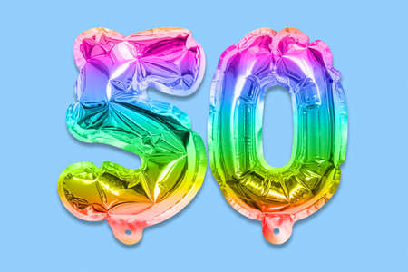 Rainbow foil balloon number, digit fifty on a blue background. Birthday greeting card with inscription 50. Anniversary concept. top view. Numerical digit. Celebration event template.の写真素材
