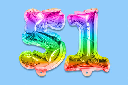 Rainbow foil balloon number, digit fifty one on a blue background. Birthday greeting card with inscription 51. Top view. Numerical digit. Celebration event template.の写真素材