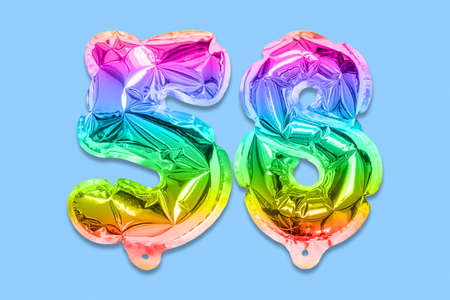 Rainbow foil balloon number, digit fifty eight on a blue background. Birthday greeting card with inscription 58. Top view. Numerical digit. Celebration event template.の写真素材