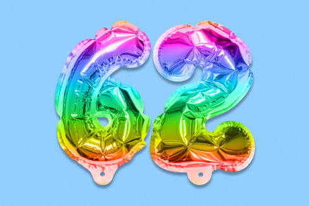 Rainbow foil balloon number, digit sixty two on a blue background. Birthday greeting card with inscription 62. Anniversary concept. top view. Numerical digit. Celebration event template.の写真素材