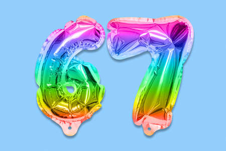 Rainbow foil balloon number, digit sixty seven on a blue background. Birthday greeting card with inscription 67. Top view. Numerical digit. Celebration event template.の写真素材