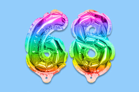 Rainbow foil balloon number, digit sixty eight on a blue background. Birthday greeting card with inscription 68. Top view. Numerical digit. Celebration event template.の写真素材