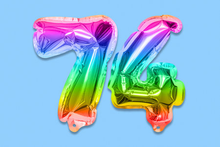 Rainbow foil balloon number, digit seventy four on a blue background. Birthday greeting card with inscription 74. Top view. Numerical digit. Celebration event template.の写真素材