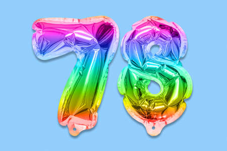 Rainbow foil balloon number, digit seventy eight on a blue background. Birthday greeting card with inscription 78. Top view. Numerical digit. Celebration event template.の写真素材