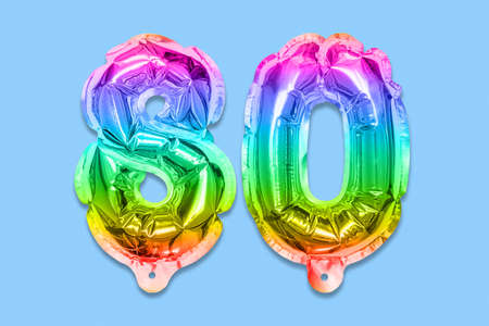 Rainbow foil balloon number, digit eighty on a blue background. Birthday greeting card with inscription 80. Anniversary concept. top view. Numerical digit. Celebration event template.の写真素材