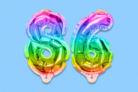 Rainbow foil balloon number, digit eighty six on a blue background. Birthday greeting card with inscription 86. Top view. Numerical digit. Celebration event template.の写真素材