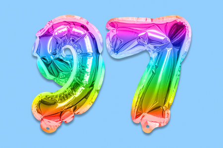 Rainbow foil balloon number, digit ninety seven on a blue background. Birthday greeting card with inscription 97. Top view. Numerical digit. Celebration event template.の写真素材