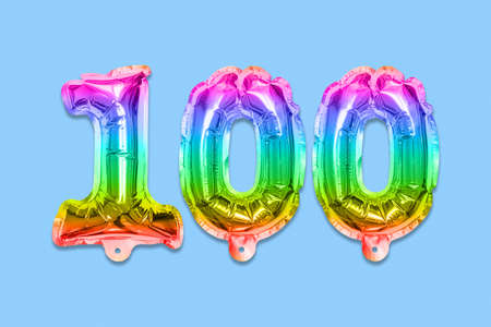 Rainbow foil balloon number, digit one hundred on a blue background. Birthday greeting card with inscription 100. Anniversary concept. Numerical digit. Celebration event template.の写真素材
