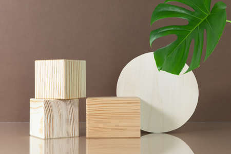 Wooden scenes on a beige table on a brown background with green monstera leaf. Premium podium for advertising your product. background for the product presentation.の写真素材