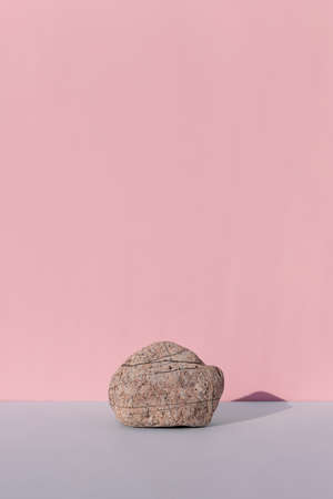 Podium made of natural stone on a gray table on a pink background. Showcase for product promotion, beauty, natural eco cosmetic. copyspace.の写真素材