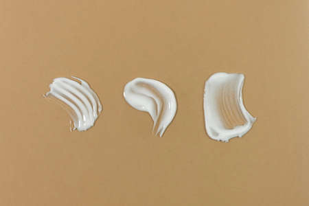 White cream texture on a beige background. Smear of skincare cosmetics product. wellness and beauty concept.の写真素材