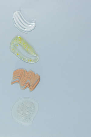 Textures of various cosmetics on a gray background. Smear of skincare cosmetics product, gel for washing, scrub, lotion, cream and serum for the face. wellness and beauty concept.の写真素材