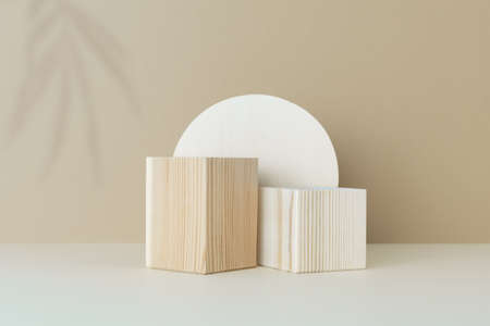 Wooden scenes with a shadow of tropical palm leaves on a light table against a beige wall background. Premium podium for advertising your product. Background for the product presentation.の写真素材