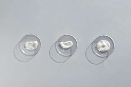 White cream textures in Petri dishes on a gray background. Concept of cosmetics laboratory researches. Smear of skincare cosmetics product. Wellness and beauty concept. Soft focusの写真素材