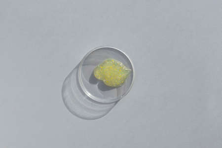 A smear, a drop of scrub in a Petri dish on a gray background. Concept of cosmetics laboratory researches. Smear of skincare cosmetics product. wellness and beauty conceptの写真素材