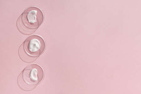White cream textures in Petri dishes on a pink background. Concept of cosmetics laboratory researches. Smear of skincare cosmetics product. Wellness and beauty concept. Soft focusの写真素材