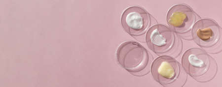 Multicolored texture of cream, scrub, serum, oil and hyaluronic acid in Petri dishes on a pink background. Concept of cosmetics laboratory researches. Smear of skincare cosmetics product. Bannerの写真素材