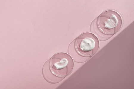 White cream textures in Petri dishes on a pink background. Concept of cosmetics laboratory...