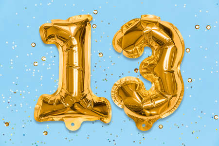The number of the balloon made of golden foil, the number thirteen on a blue background with sequins. Birthday greeting card with inscription 13. Numerical digit, Celebration event, template.の写真素材
