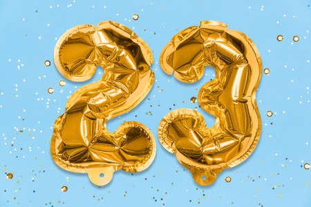 The number of the balloon made of golden foil, the number twenty three on a blue background with sequins. Birthday greeting card with inscription 23. Numerical digit, Celebration event, template.の写真素材