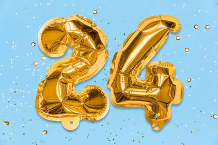 The number of the balloon made of golden foil, the number twenty-four on a blue background with sequins. Birthday greeting card with inscription 24. Numerical digit, Celebration event, template.の写真素材