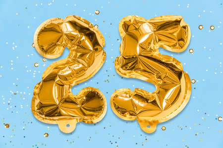 The number of the balloon made of golden foil, the number twenty-five on a blue background with sequins. Birthday greeting card with inscription 25. Numerical digit, Celebration event, template.の写真素材