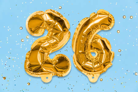 The number of the balloon made of golden foil, the number twenty-six on a blue background with sequins. Birthday greeting card with inscription 26. Numerical digit, Celebration event, template.の写真素材
