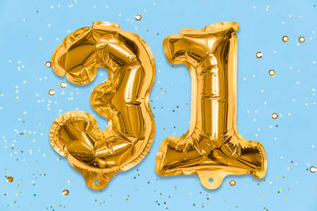The number of the balloon made of golden foil, the number thirty-one on a blue background with sequins. Birthday greeting card with inscription 31. Numerical digit, Celebration event, template.の写真素材