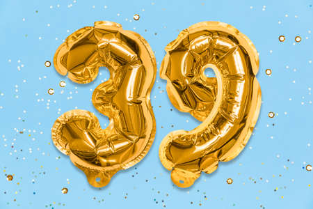 The number of the balloon made of golden foil, the number thirty-nine on a blue background with sequins. Birthday greeting card with inscription 39. Numerical digit, Celebration event, template.の写真素材