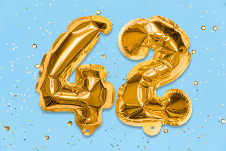 The number of the balloon made of golden foil, the number forty-two on a blue background with sequins. Birthday greeting card with inscription 42. Numerical digit, Celebration event, template.の写真素材