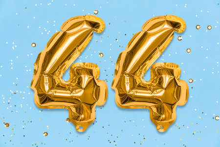 The number of the balloon made of golden foil, the number forty-four on a blue background with sequins. Birthday greeting card with inscription 44. Numerical digit, Celebration event, template.の写真素材