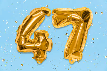 The number of the balloon made of golden foil, the number forty-seven on a blue background with sequins. Birthday greeting card with inscription 47. Numerical digit, Celebration event, template.の写真素材