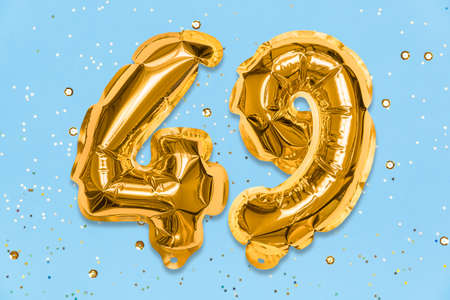The number of the balloon made of golden foil, the number forty-nine on a blue background with sequins. Birthday greeting card with inscription 49. Numerical digit, Celebration event, template.の写真素材