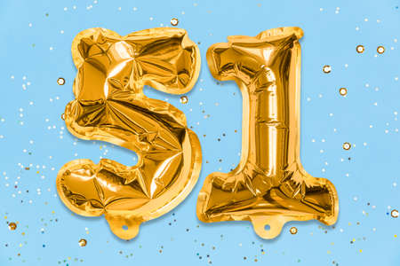 The number of the balloon made of golden foil, the number fifty-one on a blue background with sequins. Birthday greeting card with inscription 51. Numerical digit, Celebration event, template.の写真素材
