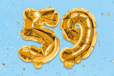 The number of the balloon made of golden foil, the number fifty-nine on a blue background with sequins. Birthday greeting card with inscription 59. Numerical digit. Celebration event template.の写真素材