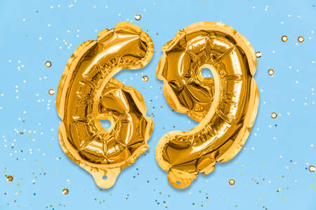 The number of the balloon made of golden foil, the number sixty-nine on a blue background with sequins. Birthday greeting card with inscription 69. Numerical digit, Celebration event, template.の写真素材