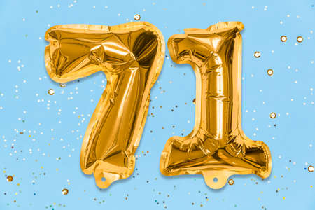 The number of the balloon made of golden foil, the number seventy-one on a blue background with sequins. Birthday greeting card with inscription 71. Numerical digit. Celebration event, template.の写真素材