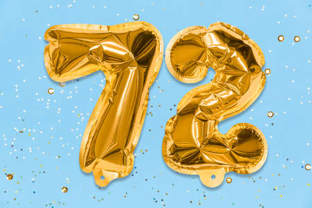 The number of the balloon made of golden foil, the number seventy-two on a blue background with sequins. Birthday greeting card with inscription 72. Numerical digit. Celebration event, template.の写真素材