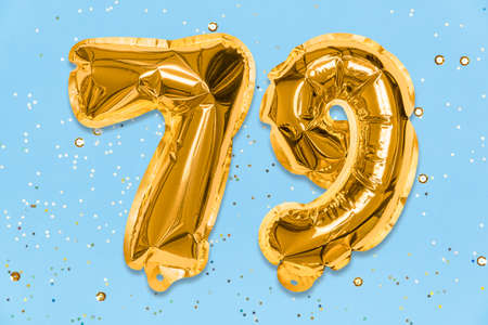 The number of the balloon made of golden foil, the number seventy-nine on a blue background with sequins. Birthday greeting card with inscription 79. Numerical digit. Celebration event, template.の写真素材