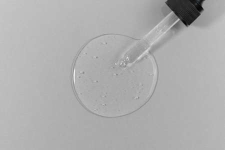 The texture of serum, gel, essential oil, lotion or hyaluronic acid with a pipette on a gray background. wellness and beauty concept.の写真素材