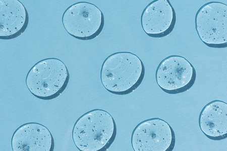 Drops of gel on a blue background. Serum or hyaluronic acid. The concept of cosmetics or virus protection.の写真素材